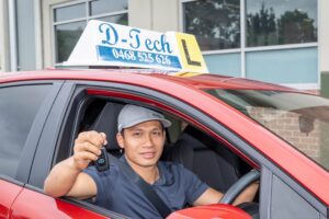 Qualified D-Tech driving instructor holding up car keys inside a dual-control training vehicle in Richmond NSW, ready for affordable driving lessons.