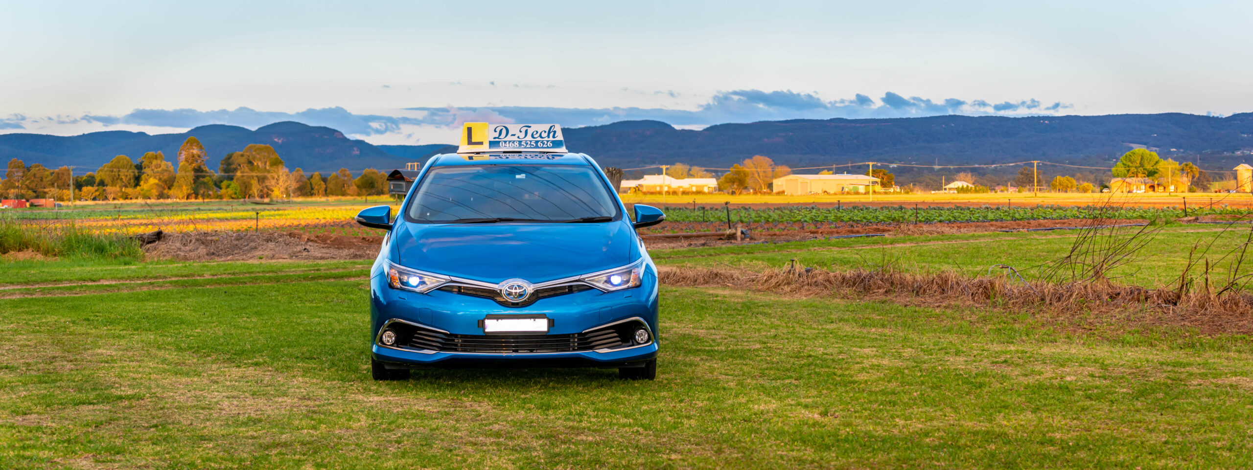 D-Tech Driver Training car on a scenic road with panoramic Blue Mountains views in Richmond NSW.
