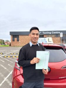 Smiling female learner driver holding her first-time practical driving test pass certificate outside the Service NSW St Marys test location.