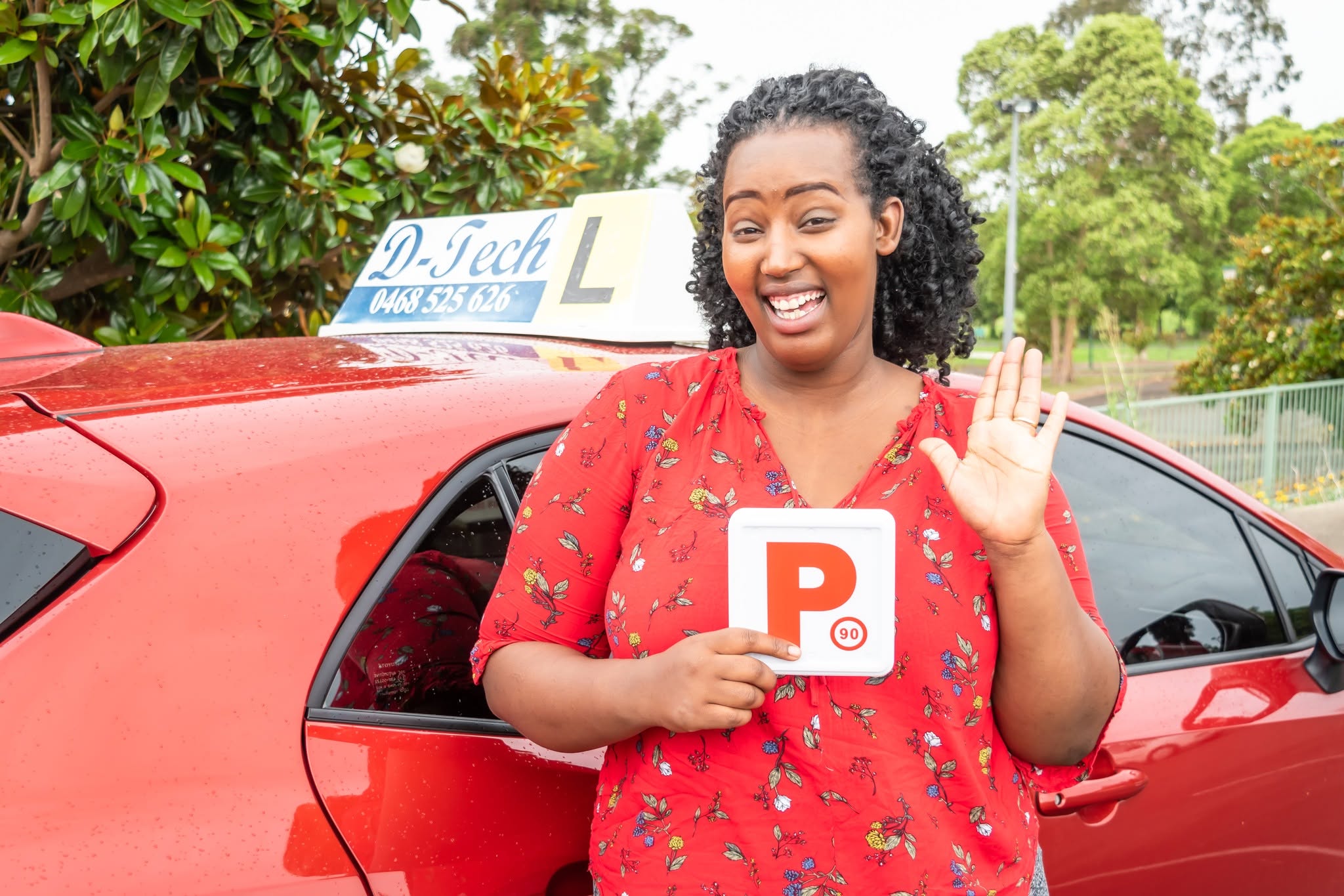 D-Tech Driver Training student smiling and holding her new NSW P-plates next to the D-Tech driving school car after passing her practical test near Ropes Crossing.
