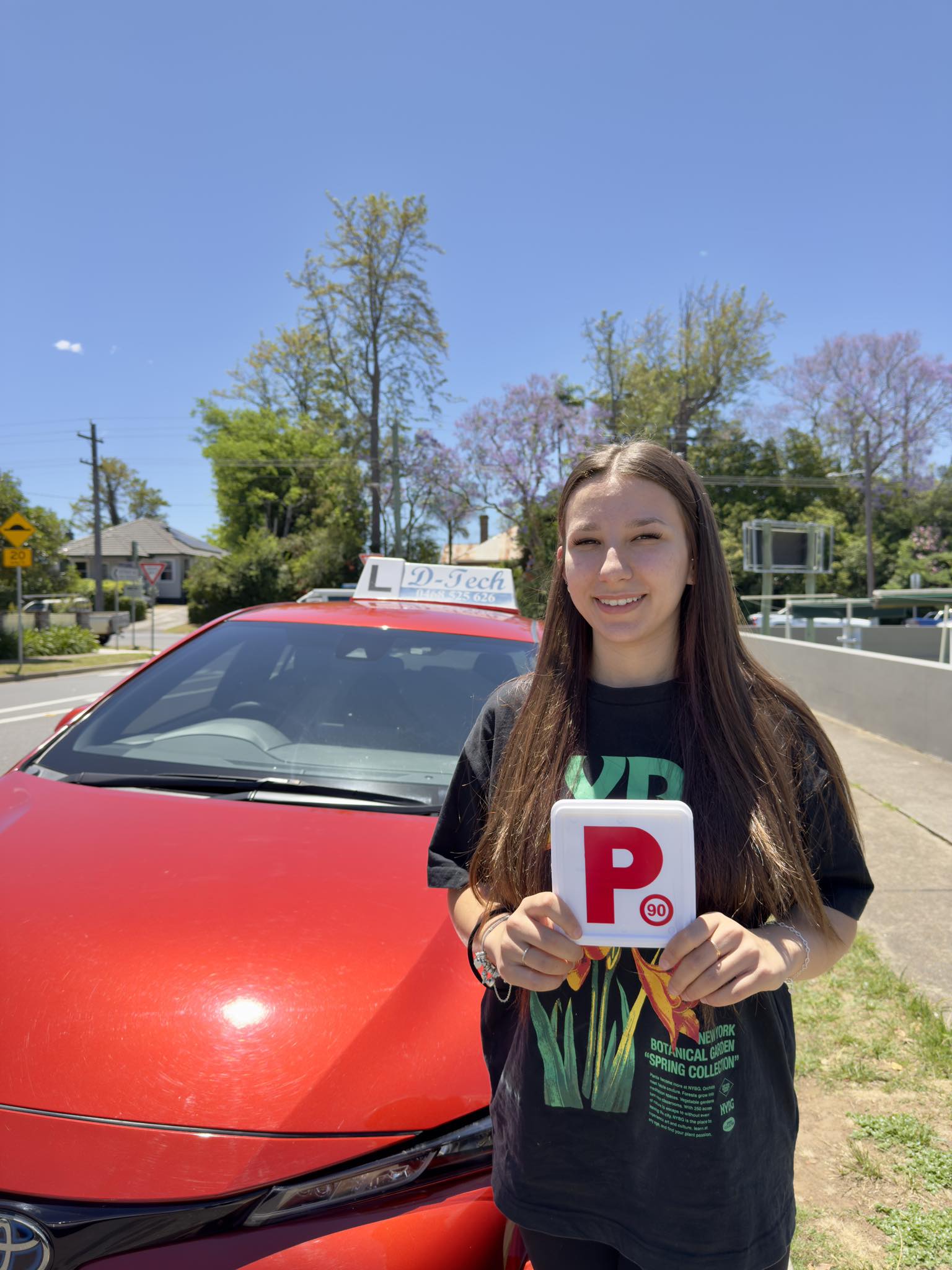 Happy student holding new P-plates after passing practical driving exam at Penrith RMS center 2.