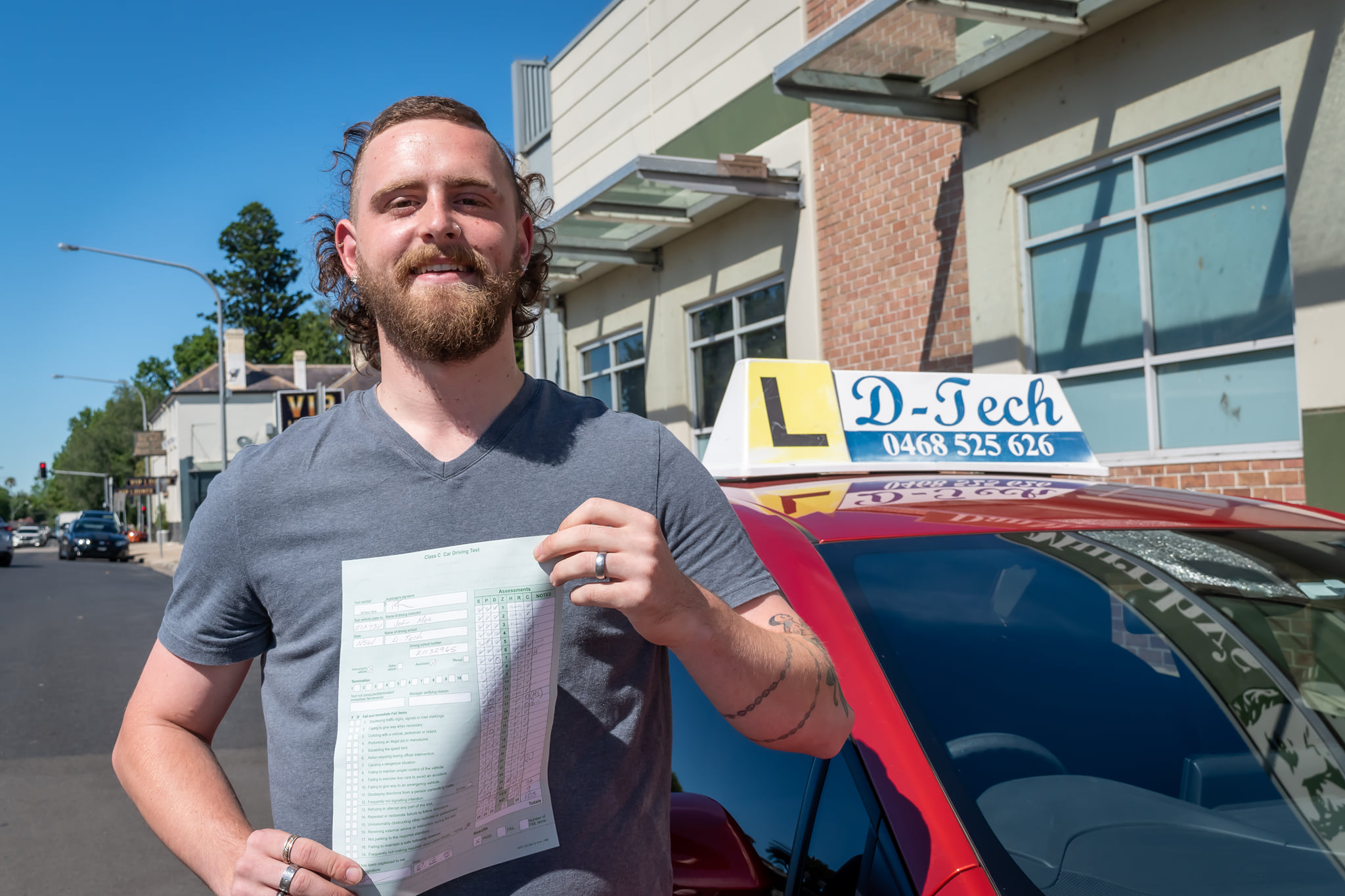 Happy student holding new P-plates after passing practical driving exam at Richmond RMS center 2.
