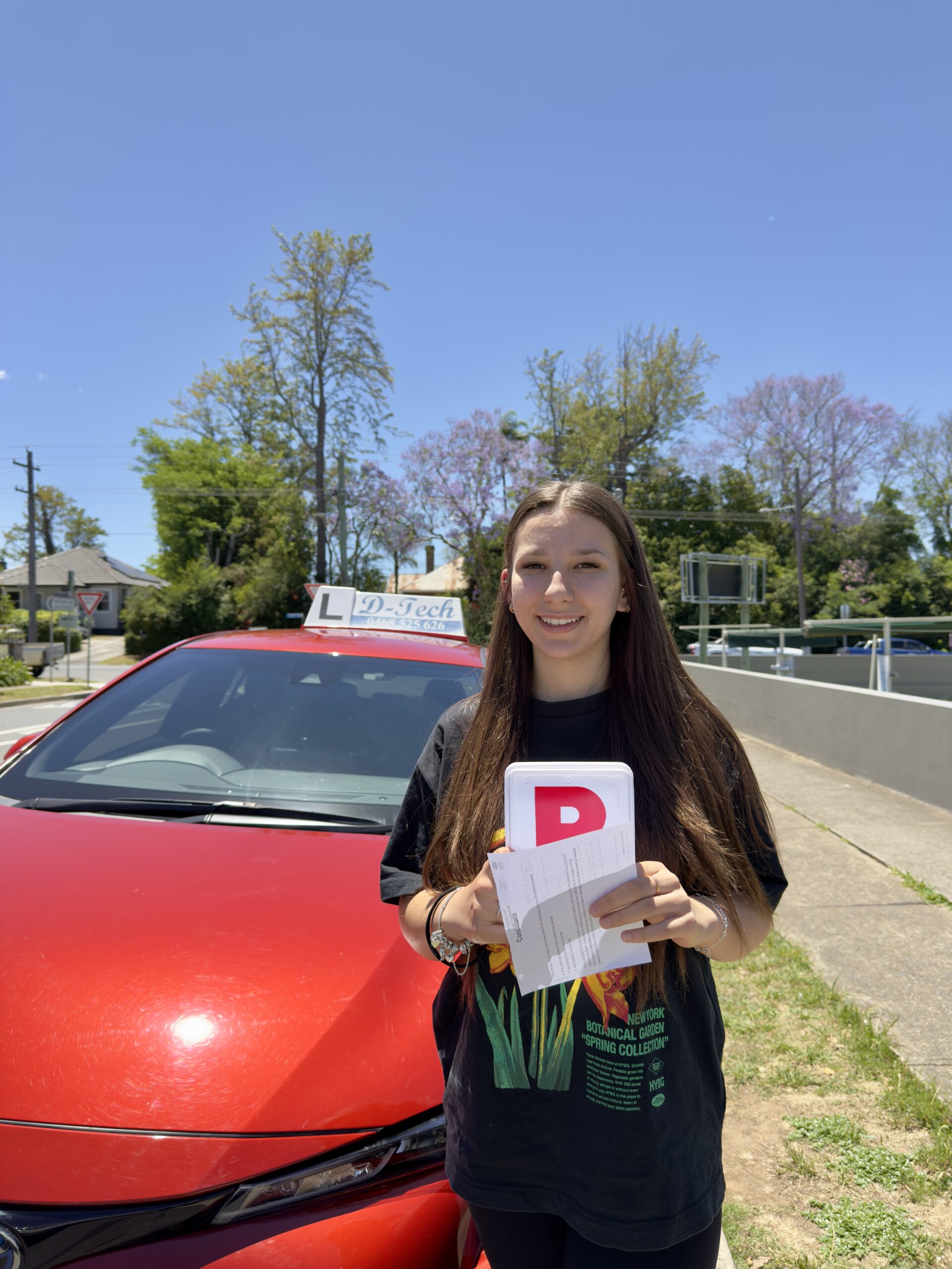 D-Tech Driver Training student holding her P-plate and pass paperwork after passing her practical test with a Hawkesbury driving school.