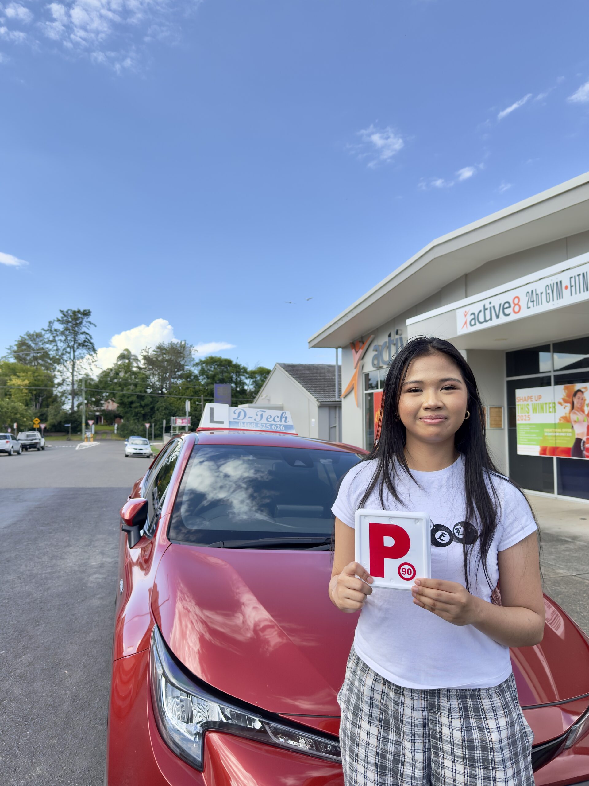 D-Tech Driver Training student proudly holding her P-plate after passing her practical driving test in the Hawkesbury region.