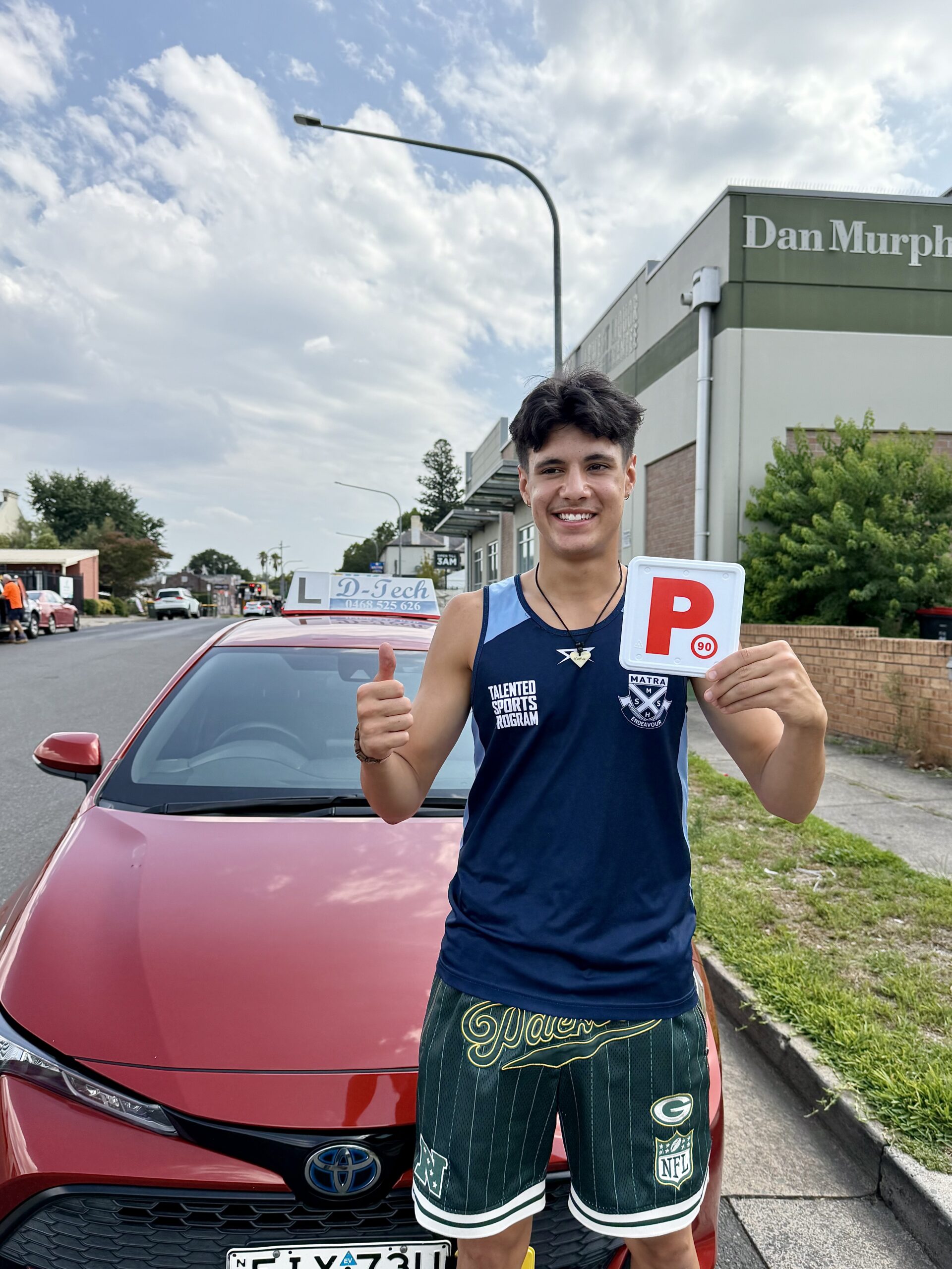 D-Tech Driver Training student Hammy giving a thumbs up and holding his P-plate after passing his practical driving test in the Hawkesbury region.