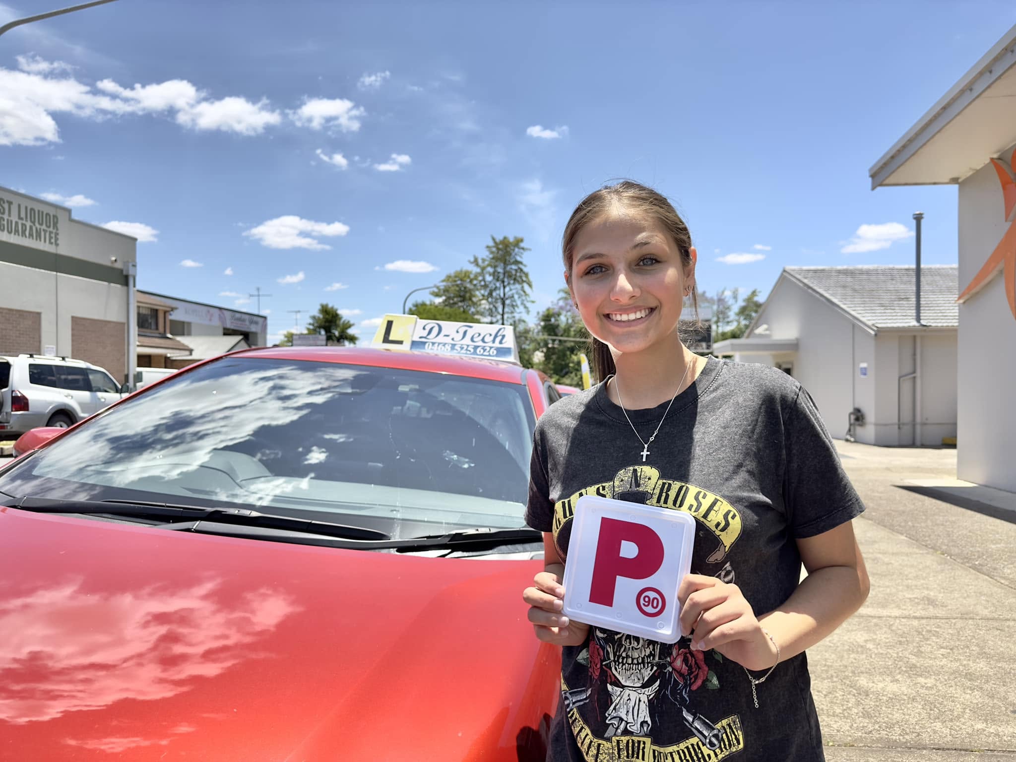 D-Tech Driver Training student Courtney holding her P-plate after passing her practical driving test at Richmond Service NSW.